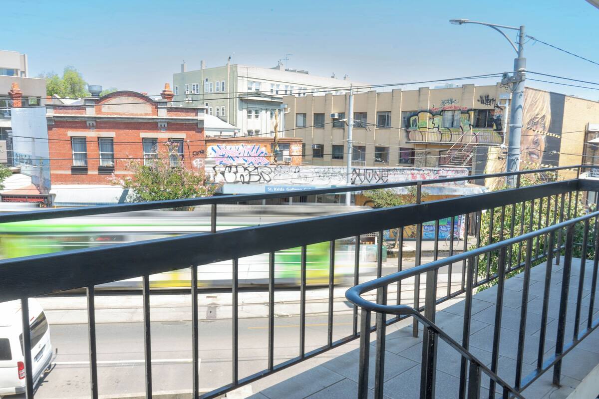 Vista de uma rua com edifícios, uma ponte e um trem passando.