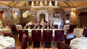 Un restaurante con paredes de ladrillo, vigas de madera y mesas dispuestas para comer.