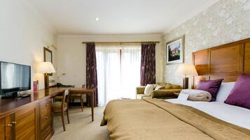 A hotel room with a bed, a desk, a television, and a window with curtains.