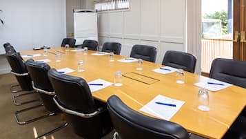 A conference room with a long table, black leather chairs, and a whiteboard.