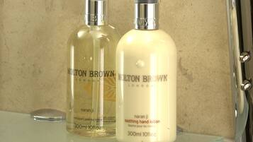 Two bottles of Molton Brown London hand lotion on a glass shelf.