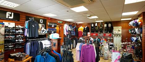 En butik der sælger golfbeklædning, med reoler fyldt med tøj, golfbags og tilbehør.