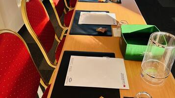 Un salón de conferencias con una larga mesa, sillas rojas y vistas amplias a través de grandes ventanales.