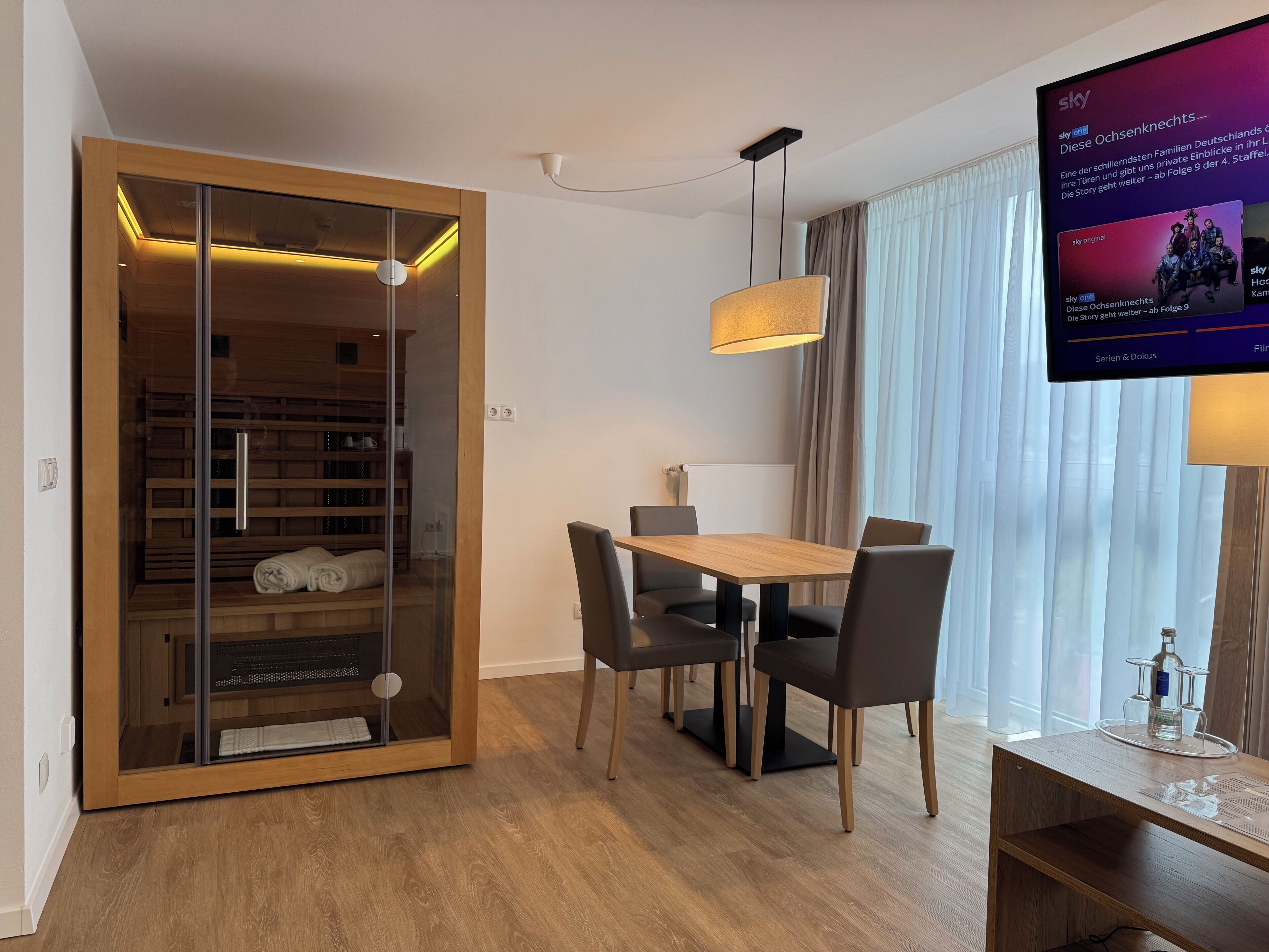A modern room with a wooden dining table, chairs, a television, and a sliding glass door closet.
