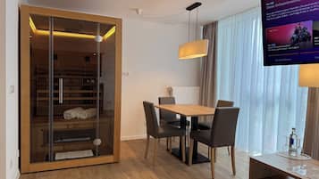 A modern room with a wooden dining table, chairs, a television, and a sliding glass door closet.