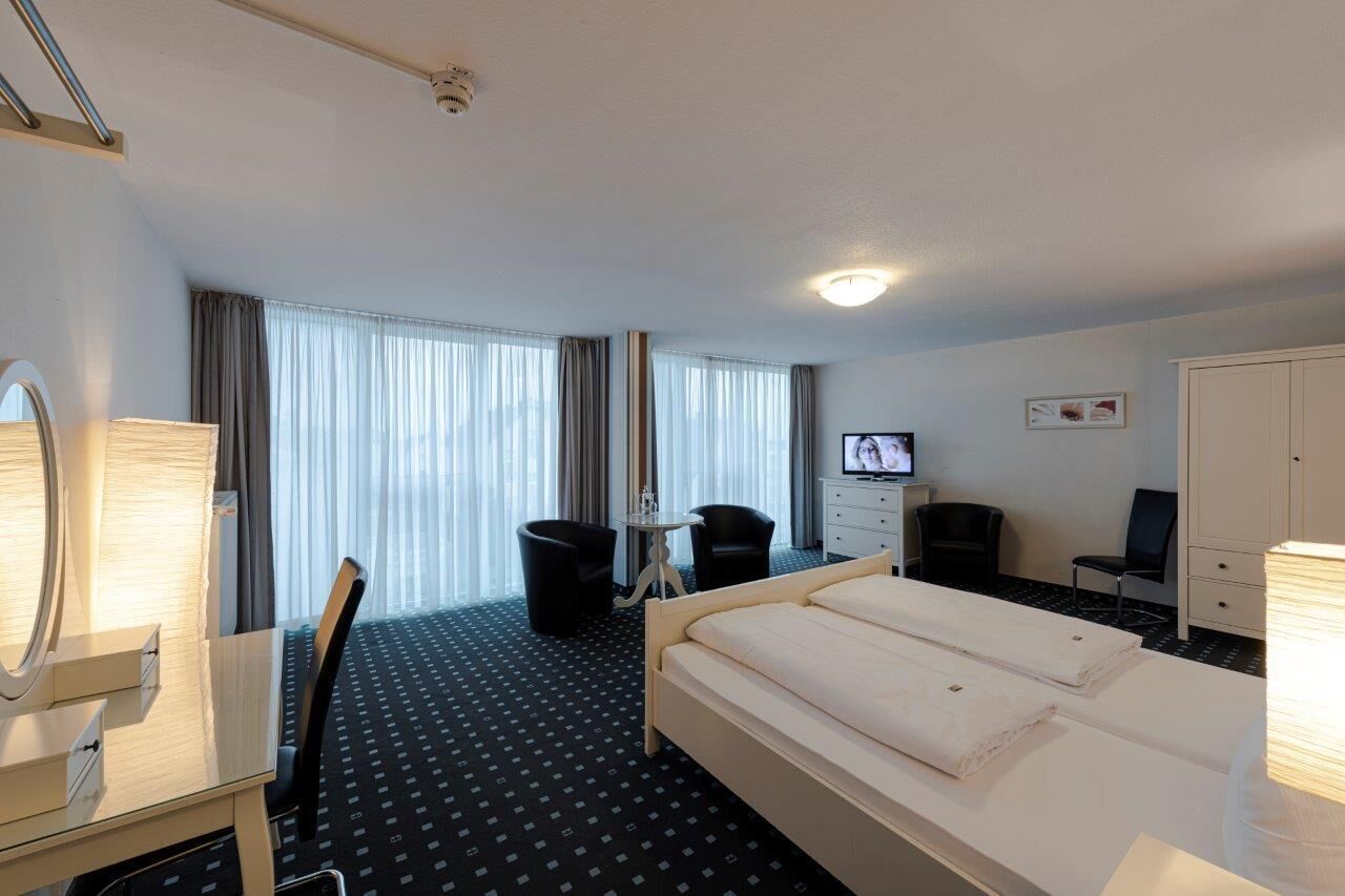 Une chambre d’hôtel équipée d’un lit, d’un bureau, d’une chaise, d’une télévision et d’une armoire.