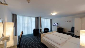 Une chambre d’hôtel équipée d’un lit, d’un bureau, d’une chaise, d’une télévision et d’une armoire.