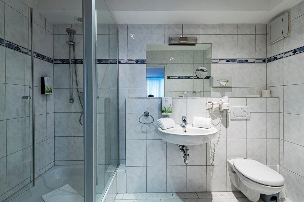 A modern bathroom with a glass-enclosed shower, a sink with a mirror, and a toilet.