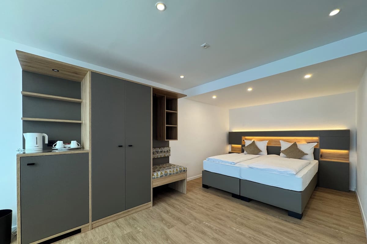 A modern bedroom with a bed, built-in wardrobe, and a small seating area.