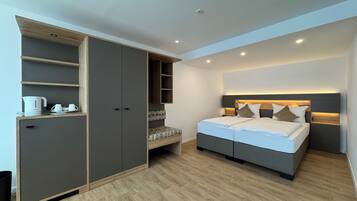 A modern bedroom with a bed, built-in wardrobe, and a small seating area.