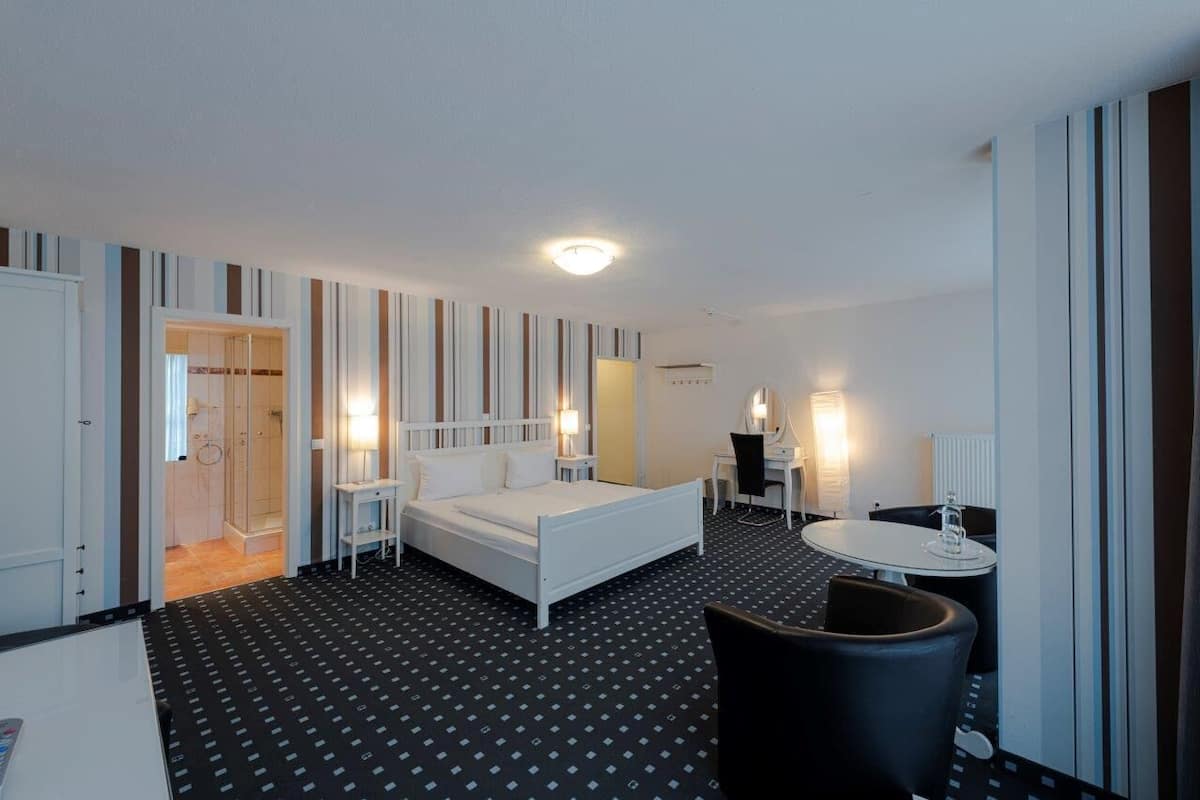 A hotel room with a bed, bedside tables, a desk, and a chair.