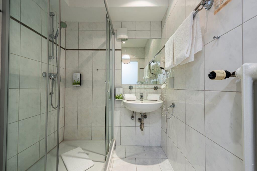 Un baño moderno con cabina de ducha de vidrio, un lavabo y un espejo.