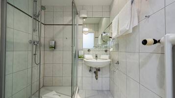 Un baño moderno con cabina de ducha de vidrio, un lavabo y un espejo.