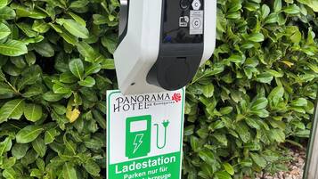 Un parcmètre avec un panneau indiquant qu’il s’agit d’une borne de recharge pour véhicules électriques, situé à l’hôtel Panorama.
