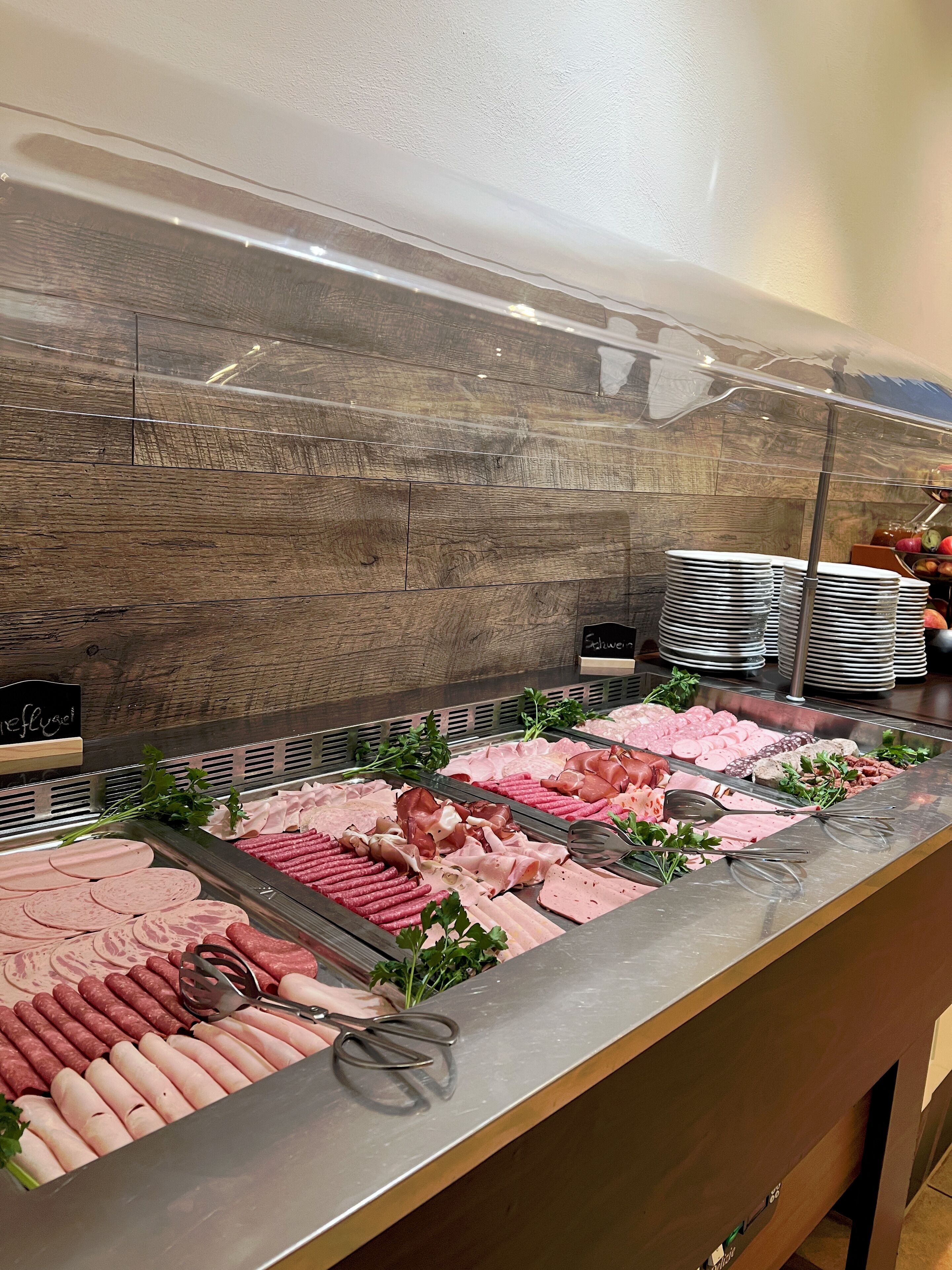 Ein Buffet mit verschiedenen Fleischsorten und einer Stapel Teller.