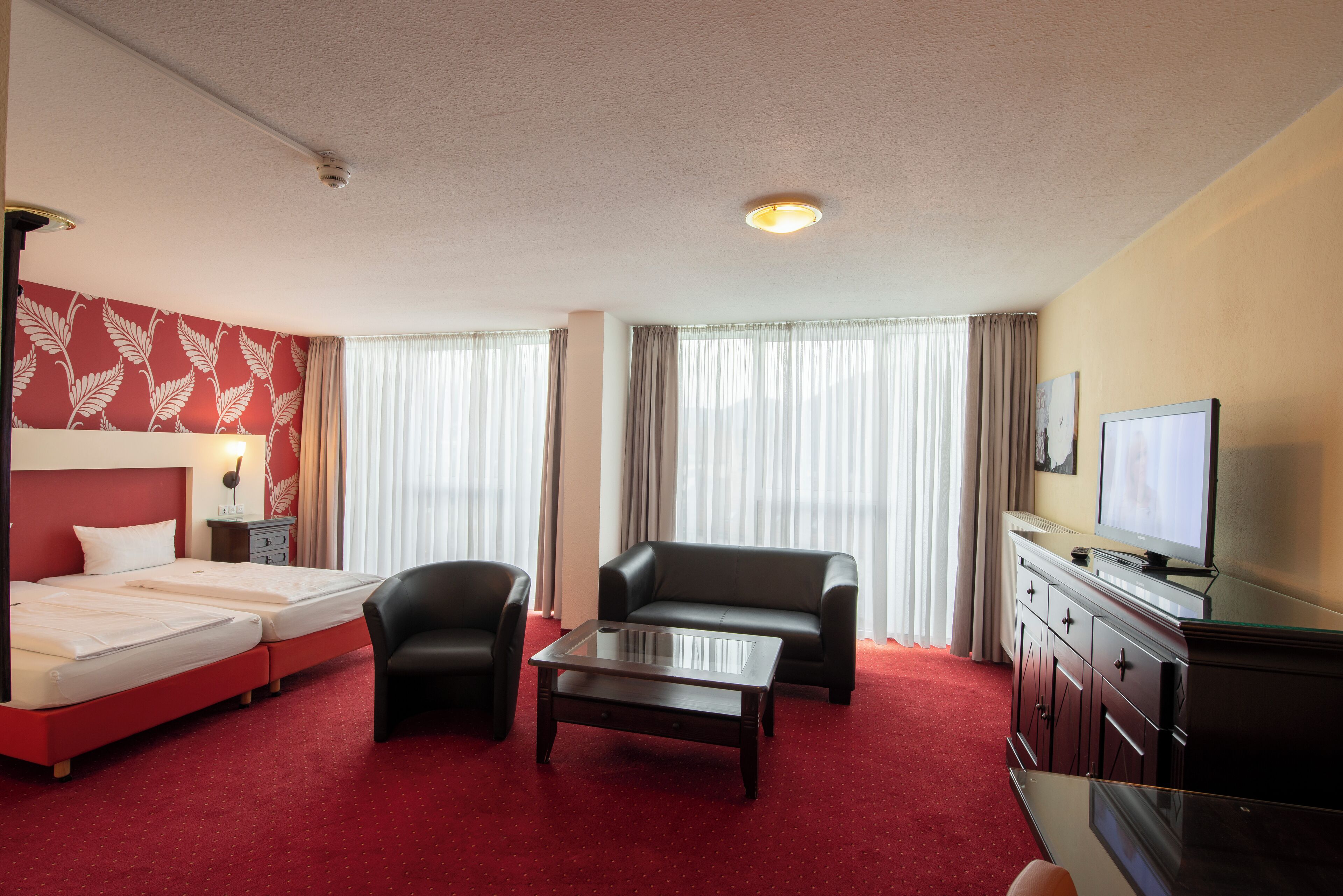 Una habitación de hotel con cama, sofá, mesita de café, televisor y escritorio.