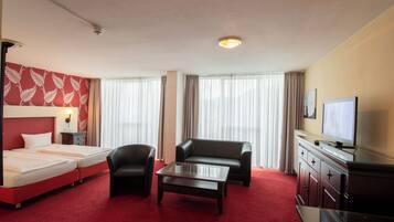Una habitación de hotel con cama, sofá, mesita de café, televisor y escritorio.
