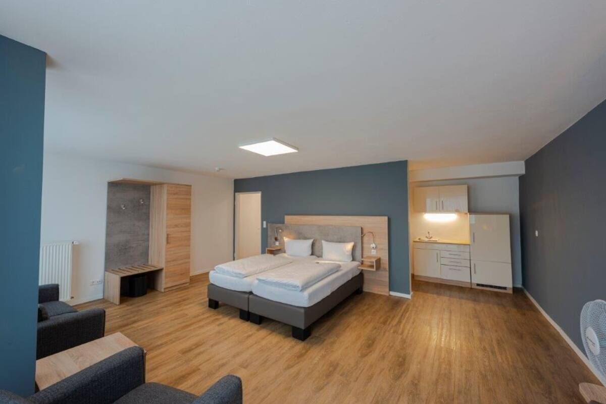 A modern bedroom with a double bed, bedside tables, a small desk, and a chair.