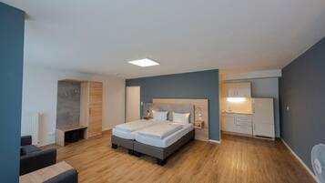 Een moderne slaapkamer met een tweepersoonsbed, nachtkastjes, een klein bureau en een stoel.