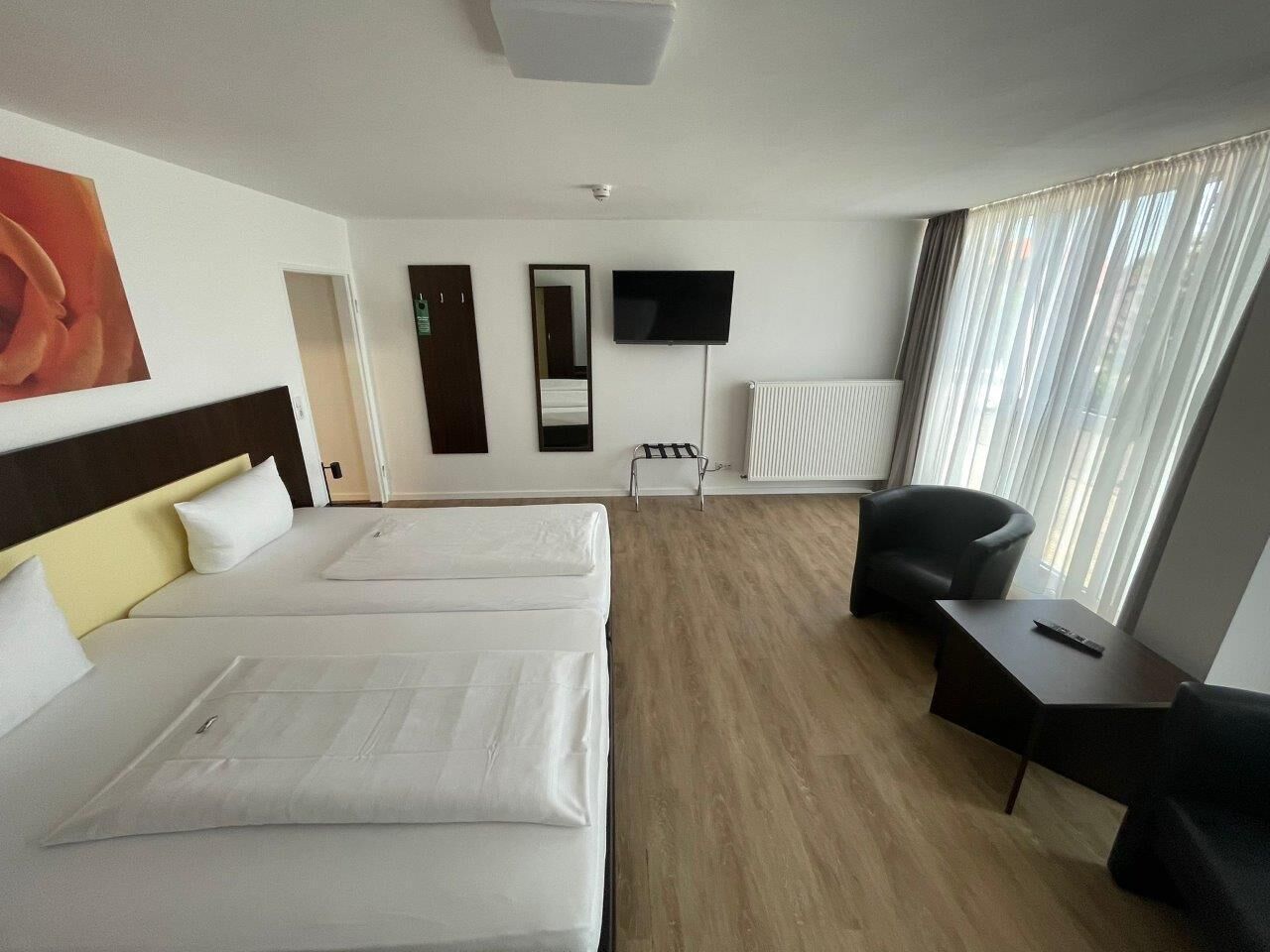 Ein Hotelzimmer mit zwei Betten, einem Flachbildfernseher, einem Schreibtisch und einem Stuhl.