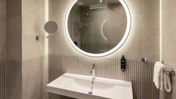 Un baño moderno con un espejo redondo, un lavamanos rectangular y un perchero para toallas.