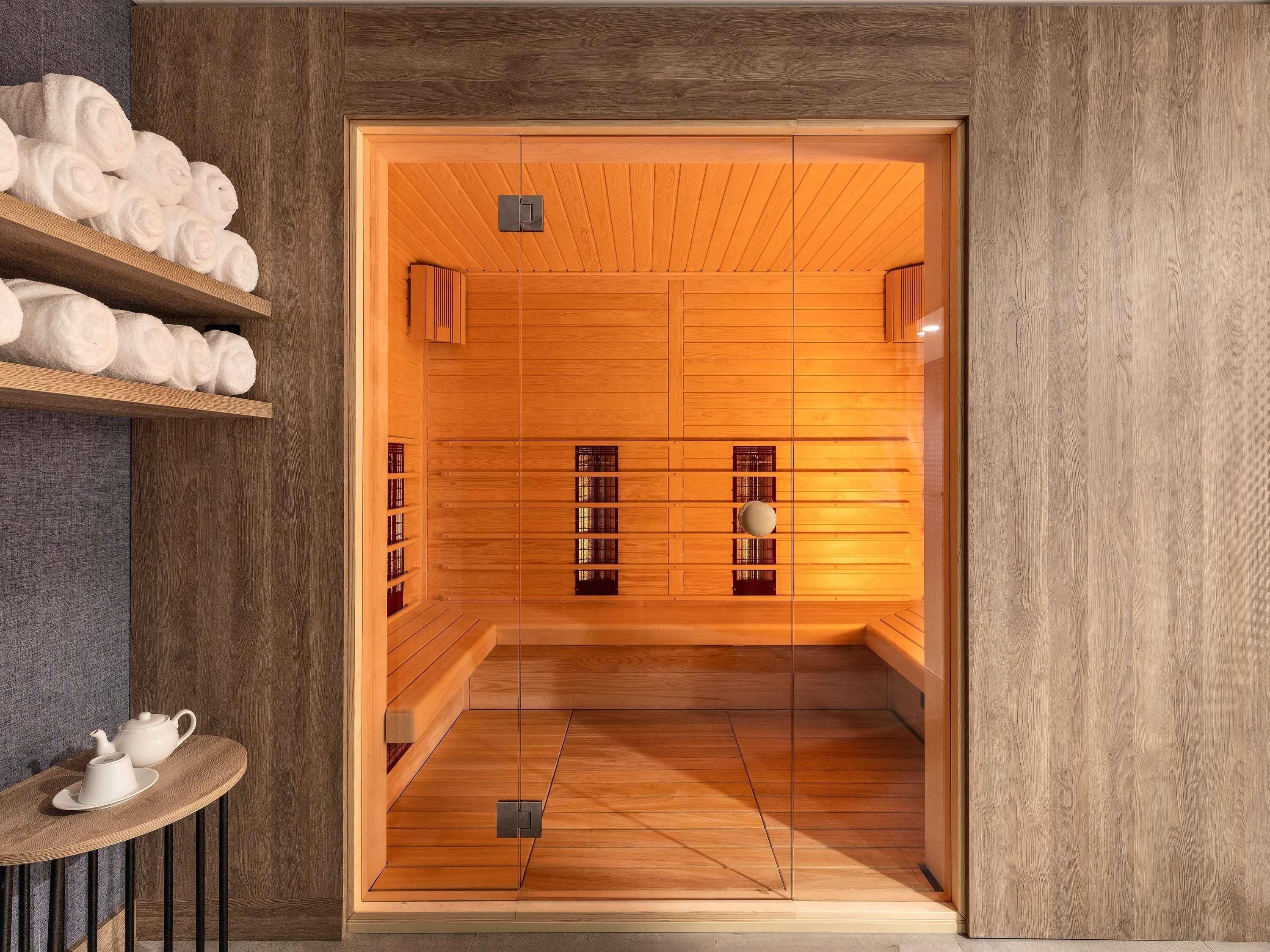 Een sauna met houten wanden, een bank en een plank met handdoeken.