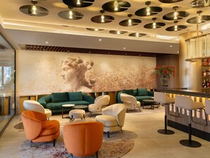 A modern lobby with a large mural, seating areas, and a bar. - Mercure Sofia City  (Sofia)