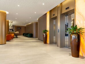 A hotel lobby with a reception desk, seating area, and an elevator. - Mercure Sofia City  (Sofia)