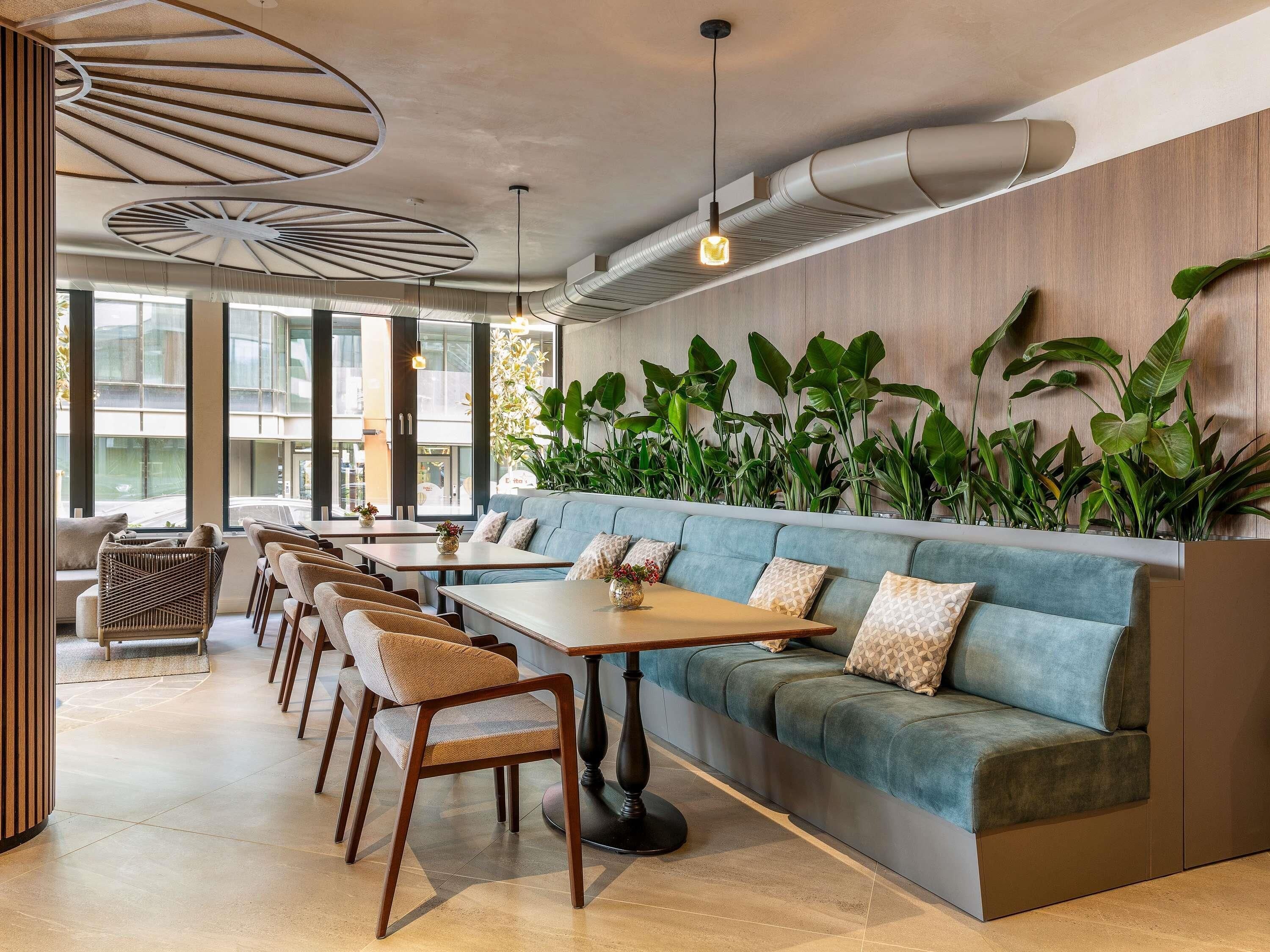 Un intérieur moderne avec un long espace salon, des tables en bois et de grandes fenêtres.