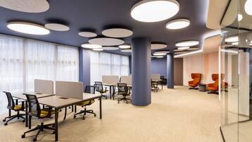 A modern office space with cubicles, ergonomic chairs, and a glass partition wall.