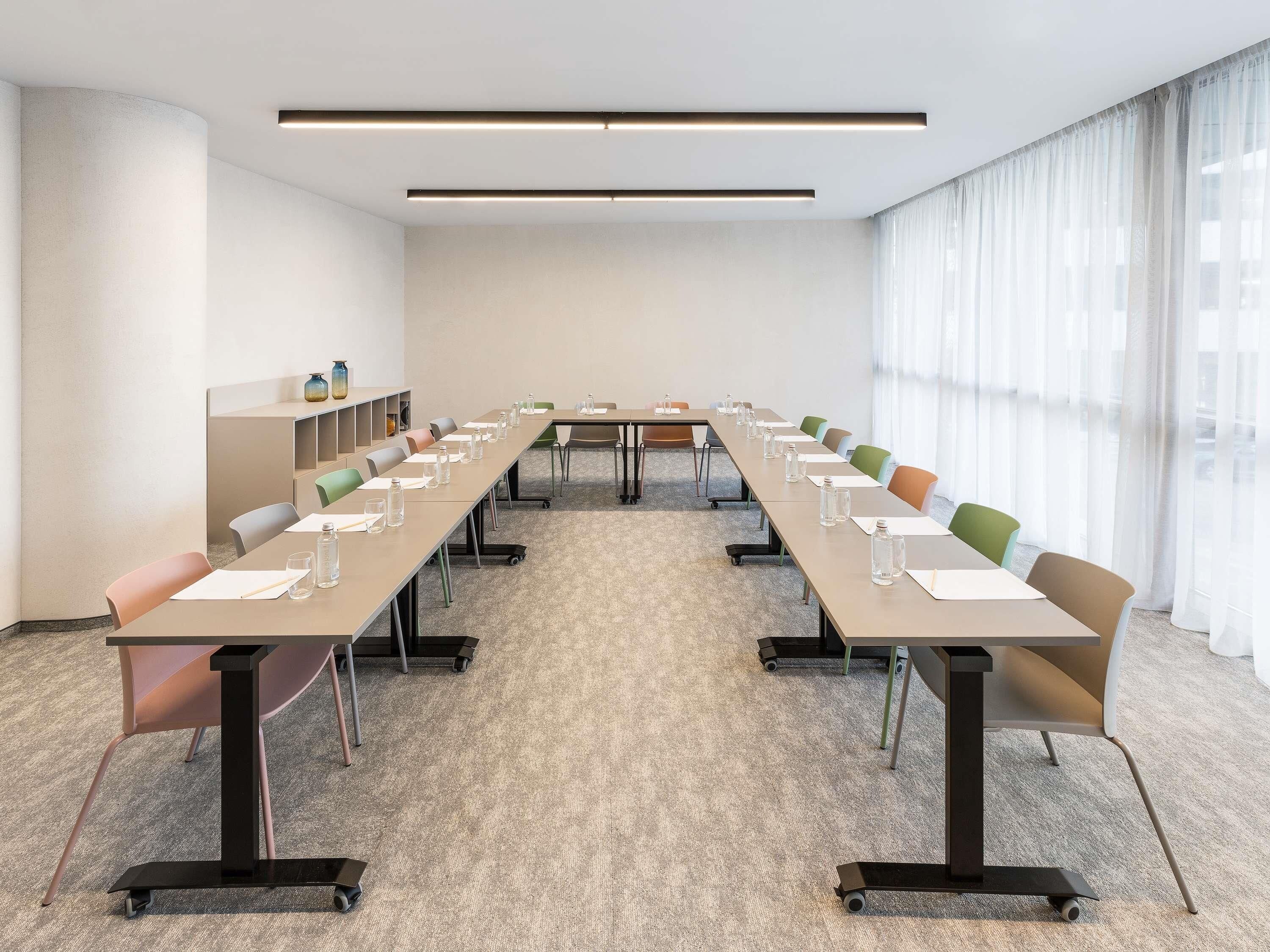 A conference room with a long table, chairs, and a carpeted floor.