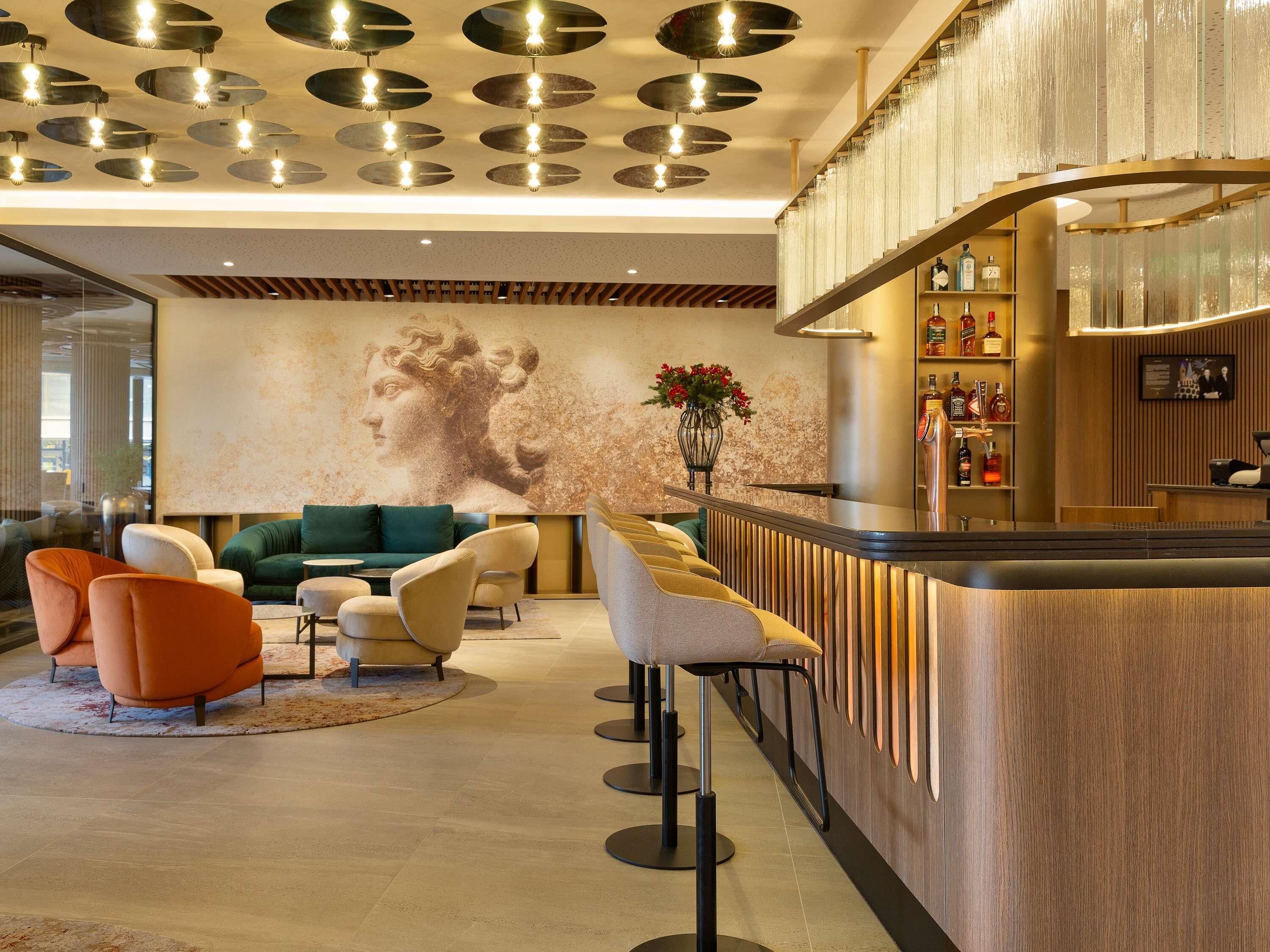 Eine moderne Lobby mit Barbereich, Sitzgelegenheiten und einem großen Wandbild.