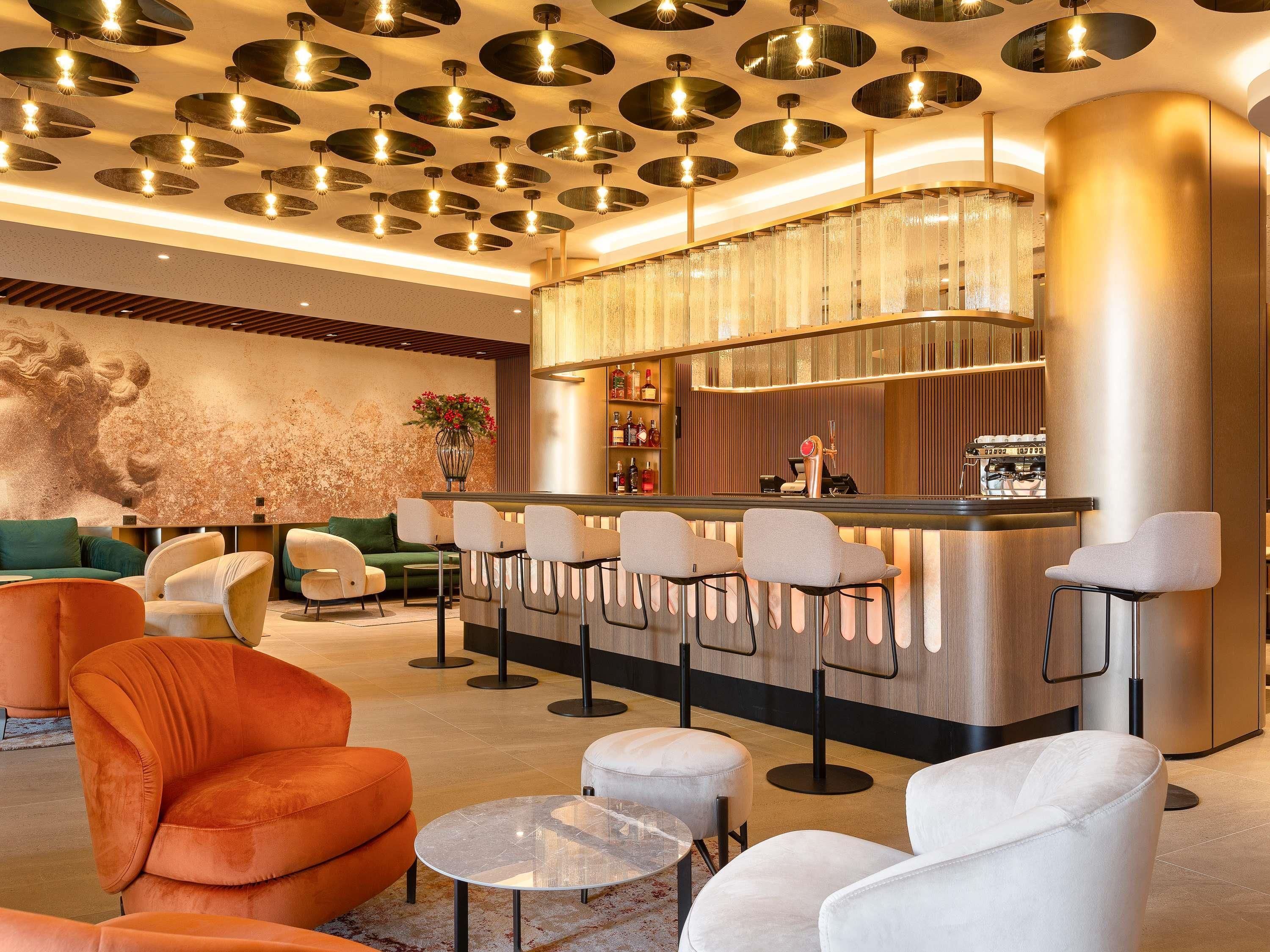 A modern bar area with a bar counter, seating, and a decorative ceiling with circular light fixtures.