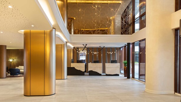 A spacious lobby with a high ceiling, a reception desk, and a staircase leading to an upper level. - Mercure Sofia City  (Sofia)