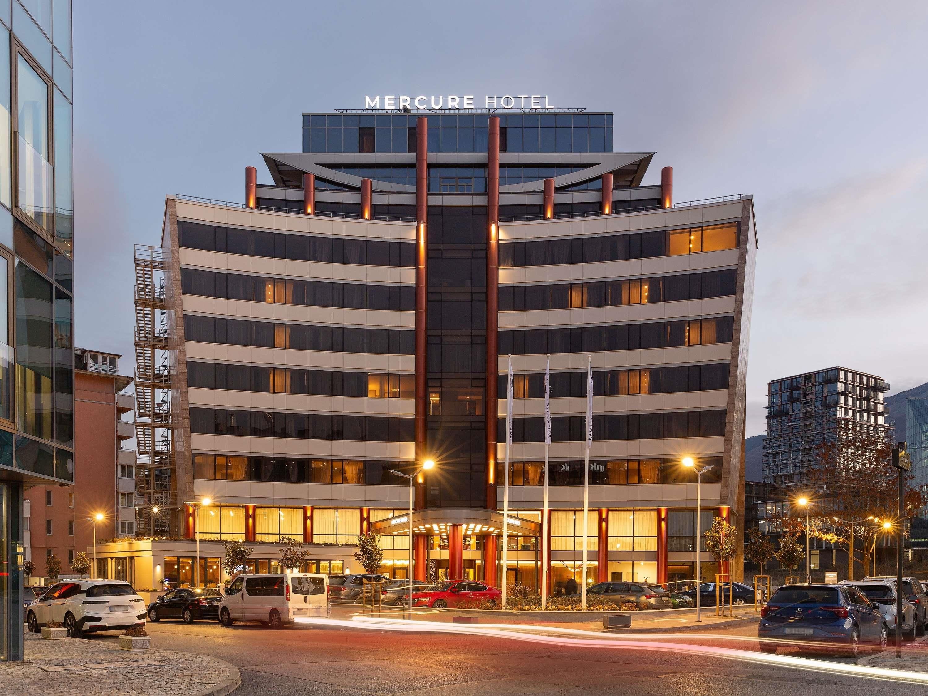 Een hotel met meerdere verdiepingen, met een modern ontwerp en een opvallende naam bovenin.