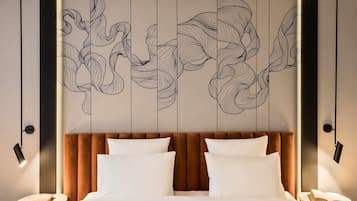 A modern hotel room with a large bed, two bedside tables, and a decorative wall panel.