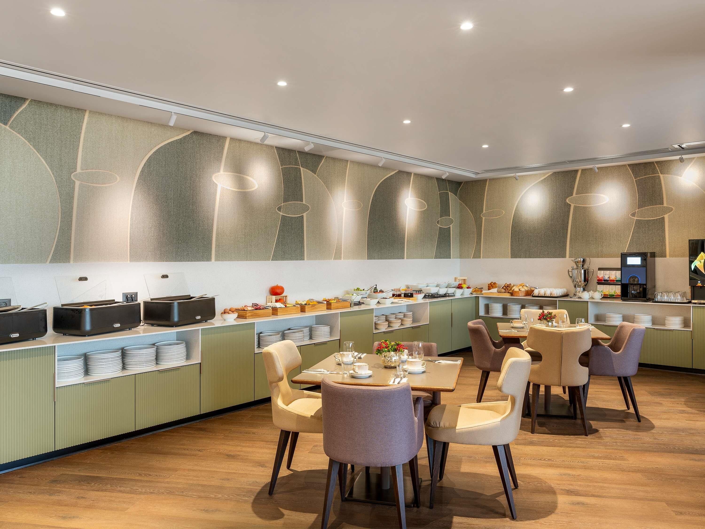 A modern dining area with a long counter, multiple seating options, and a variety of food and drink stations.