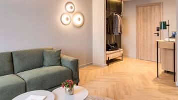 Una sala moderna con un sofá, dos mesas redondas, un pequeño jarrón decorativo y una puerta de madera.