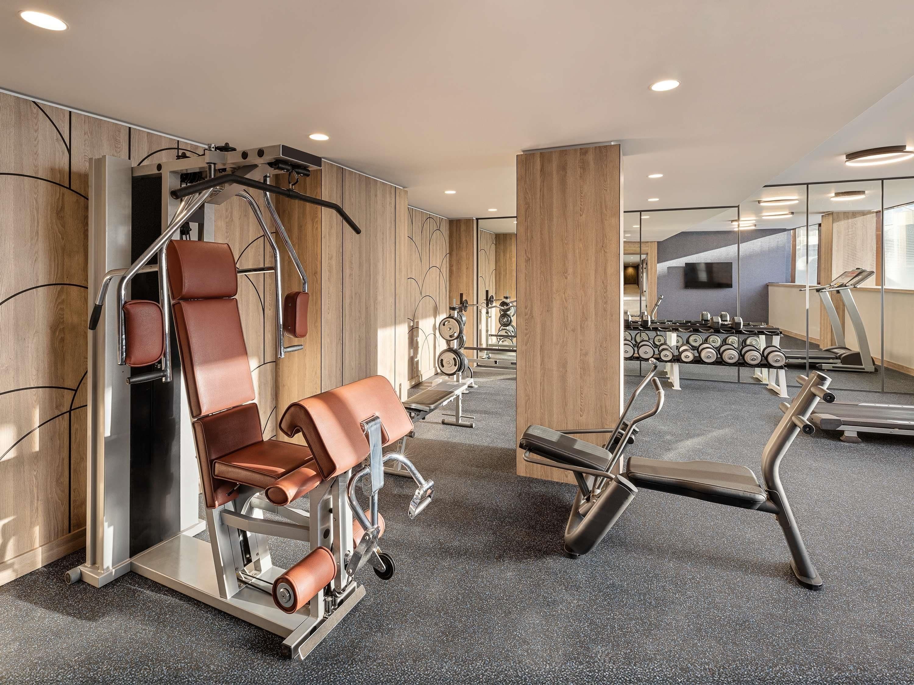 A gym with exercise equipment, a treadmill, and a mirror.