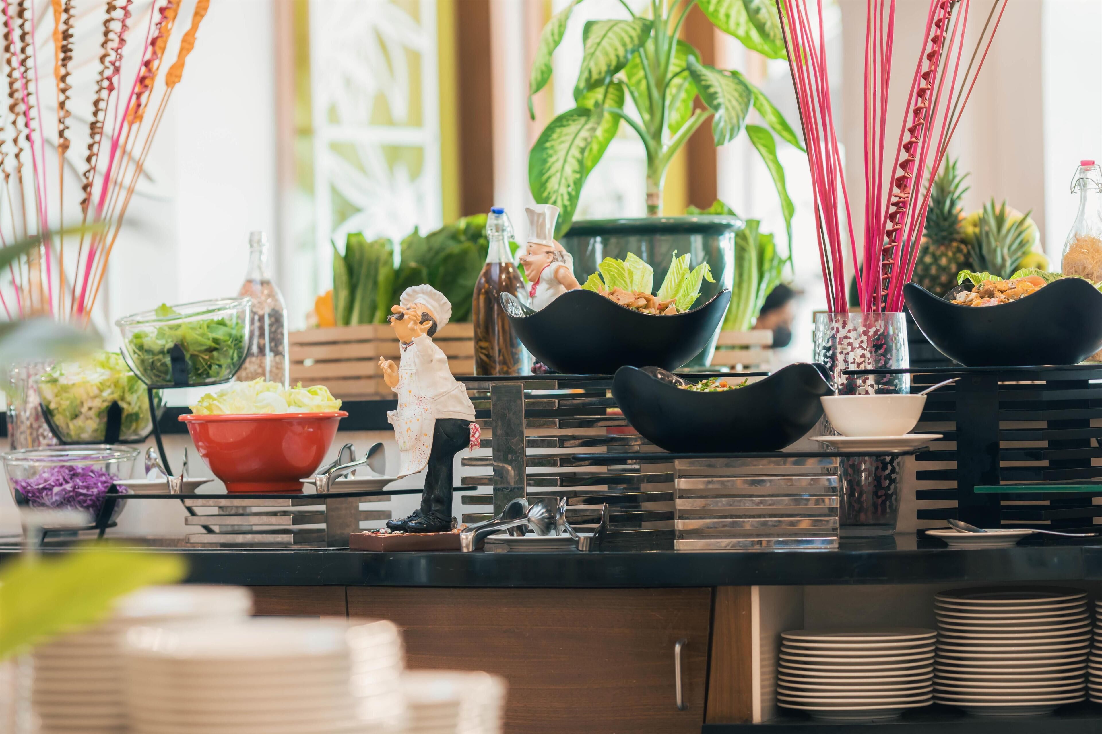 Uma mesa de buffet com diversos alimentos e uma miniatura de cozinheiro.