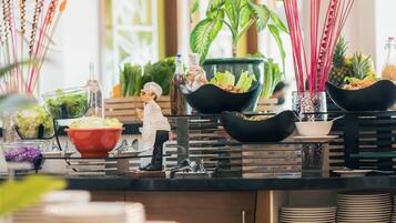 Uma mesa de buffet com diversos alimentos e uma miniatura de cozinheiro.