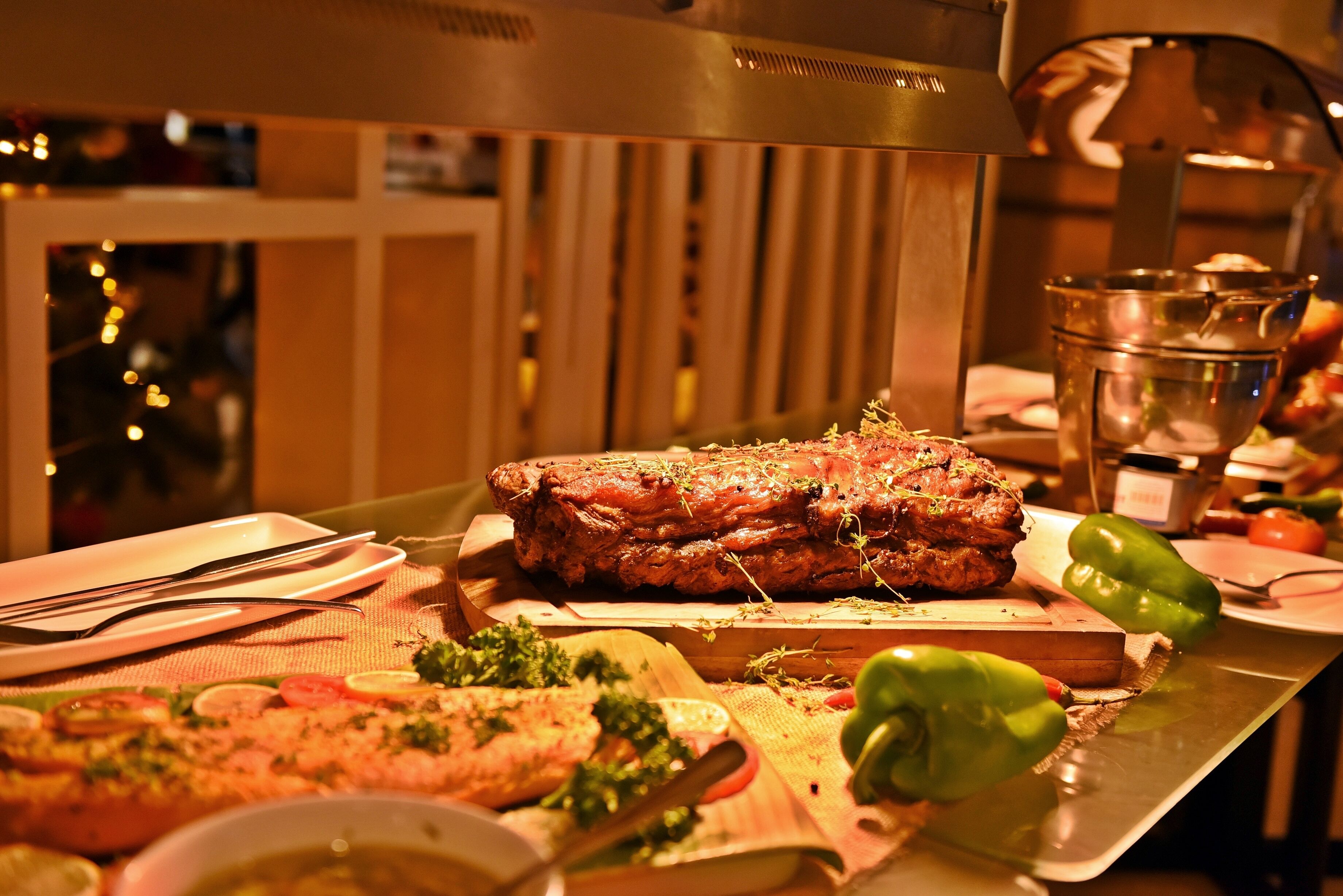 A buffet setup with a variety of dishes, including a large meat dish, vegetables, and a salad.