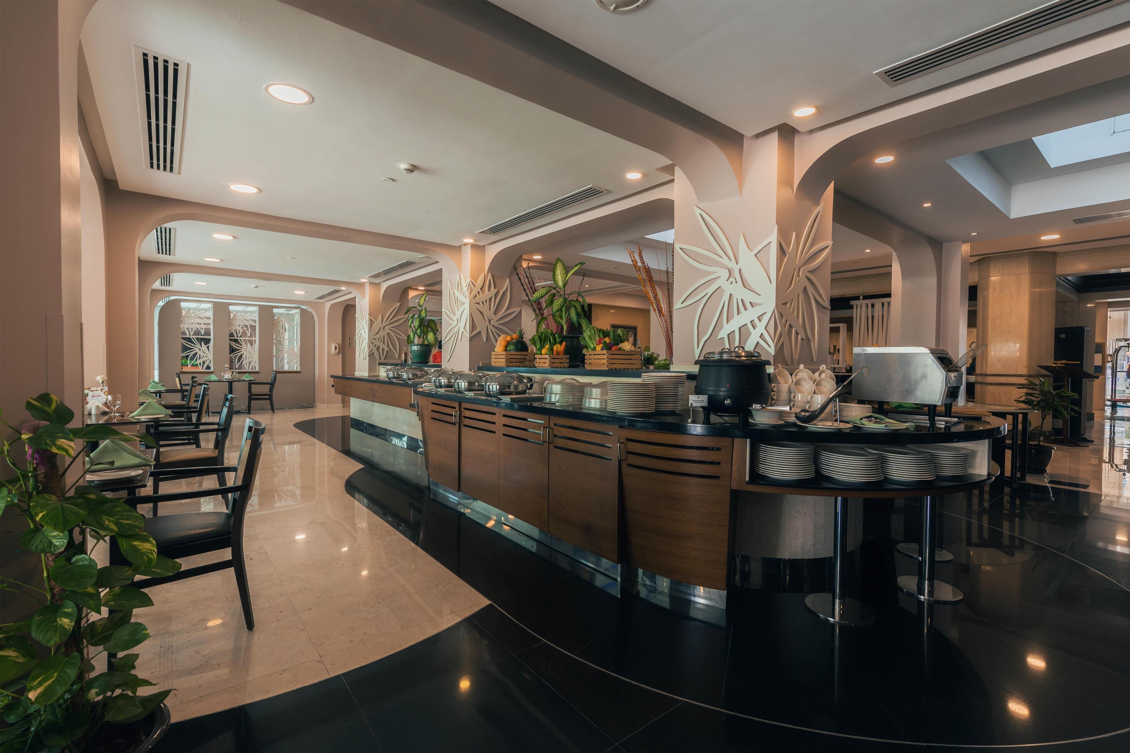 Eine moderne Hotelhalle mit einer zentralen Inselloge, einer Sitzgelegenheit und dekorativen Pflanzenarrangements.