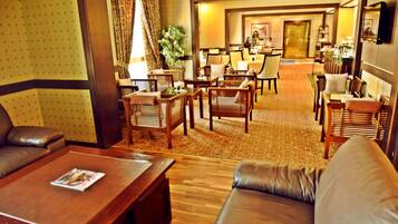 A hotel lobby with leather sofas, wooden tables, and a carpeted floor.
