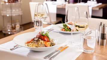 A dining table set with plates of food, wine glasses, and cutlery.