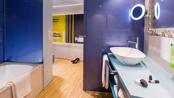 A modern bathroom with a large bathtub, a sink with a mirror, and a vanity with toiletries.