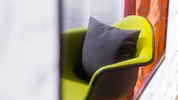 A modern chair with a dark cushion in a room with a patterned curtain.