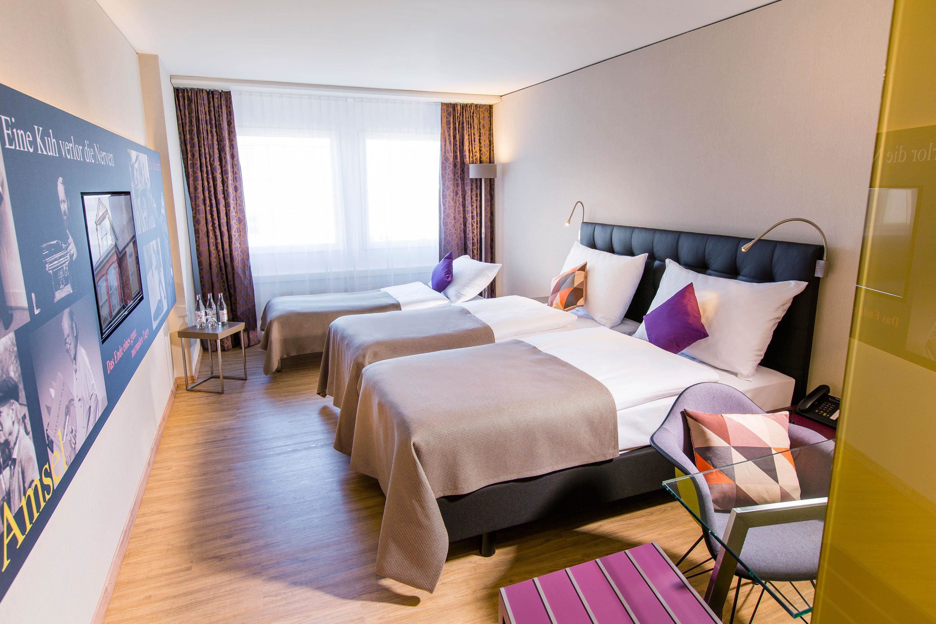 A hotel room with two beds, a desk, and a chair.