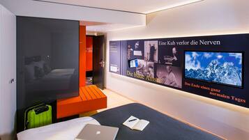 Une chambre d’hôtel moderne équipée d’un lit, d’un bureau, d’un ordinateur portable et d’une télévision.