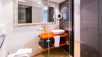 A modern bathroom with a large mirror, a white sink, and a glass shower enclosure.